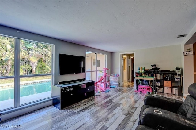 living room with a textured ceiling and light wood-type flooring