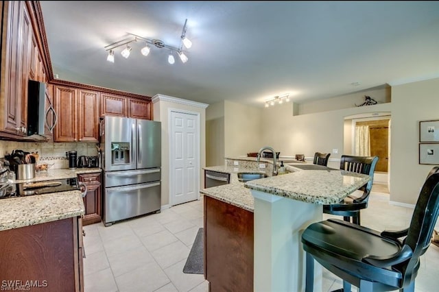 kitchen with sink, tasteful backsplash, a center island with sink, a kitchen breakfast bar, and stainless steel appliances