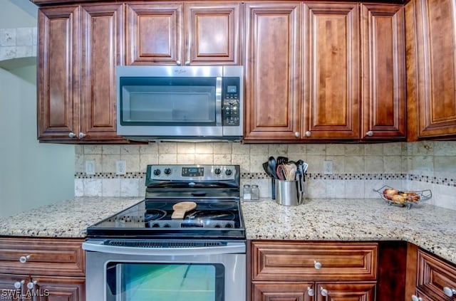 kitchen with stainless steel appliances, tasteful backsplash, and light stone counters