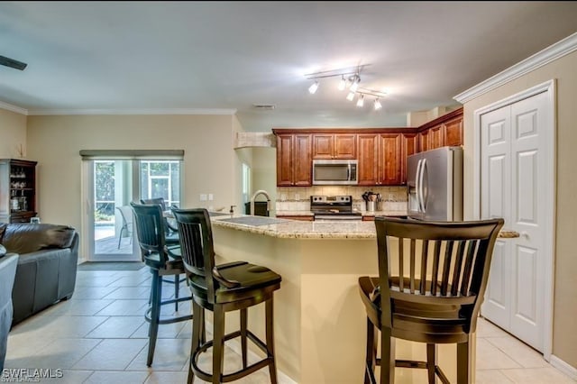 kitchen featuring crown molding, appliances with stainless steel finishes, a breakfast bar, and decorative backsplash