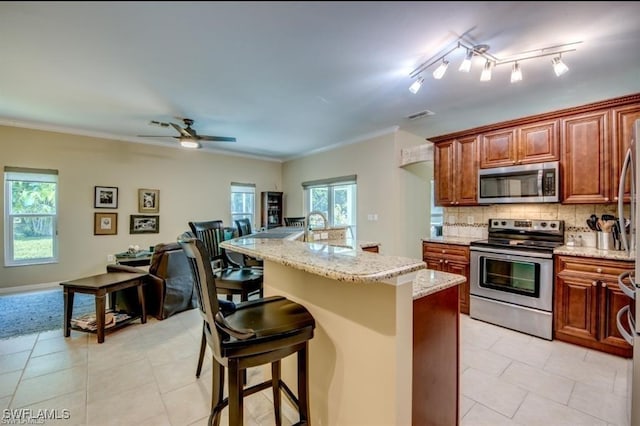 kitchen featuring sink, appliances with stainless steel finishes, backsplash, a kitchen breakfast bar, and an island with sink