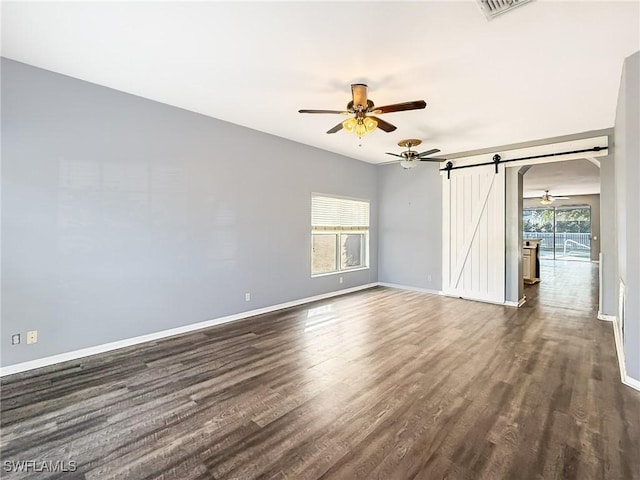 unfurnished room featuring ceiling fan, dark hardwood / wood-style floors, a barn door, and a healthy amount of sunlight