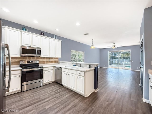 kitchen with pendant lighting, white cabinetry, sink, kitchen peninsula, and stainless steel appliances