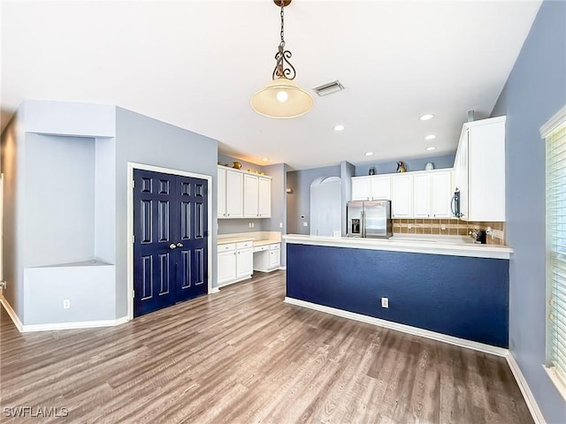 kitchen featuring pendant lighting, stainless steel appliances, tasteful backsplash, light hardwood / wood-style floors, and white cabinets