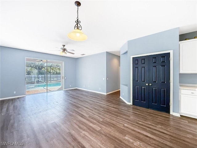 unfurnished living room featuring dark wood-type flooring and ceiling fan