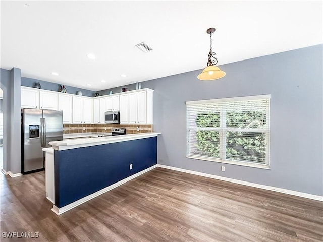 kitchen featuring white cabinetry, decorative backsplash, appliances with stainless steel finishes, and hanging light fixtures