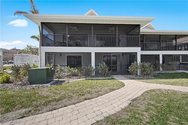 rear view of property featuring a yard, a sunroom, and ceiling fan