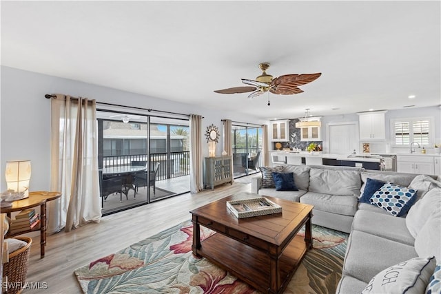 living room with ceiling fan, sink, light wood-type flooring, and a wealth of natural light