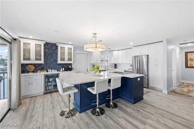 kitchen with wine cooler, a center island, stainless steel fridge, pendant lighting, and white cabinets