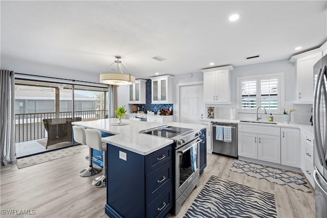 kitchen featuring pendant lighting, a kitchen island, white cabinets, and appliances with stainless steel finishes