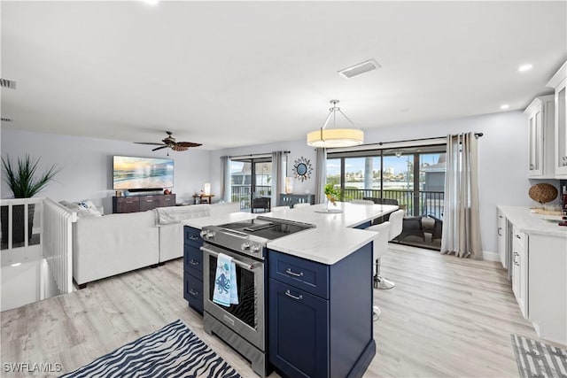 kitchen featuring stainless steel electric range oven, a kitchen island, pendant lighting, white cabinetry, and blue cabinetry