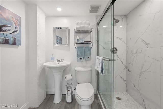 bathroom with toilet, an enclosed shower, and sink