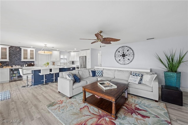 living room featuring wine cooler, ceiling fan, and light hardwood / wood-style flooring