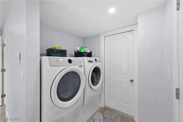 washroom featuring washing machine and clothes dryer and light hardwood / wood-style flooring