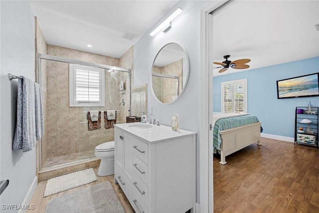 bathroom with a shower with shower door, hardwood / wood-style flooring, vanity, ceiling fan, and toilet