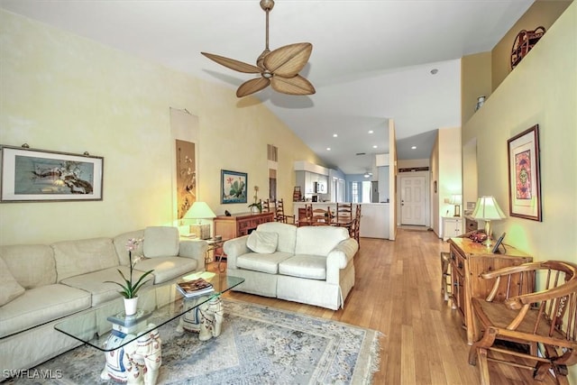 living room with high vaulted ceiling, ceiling fan, and light wood-type flooring