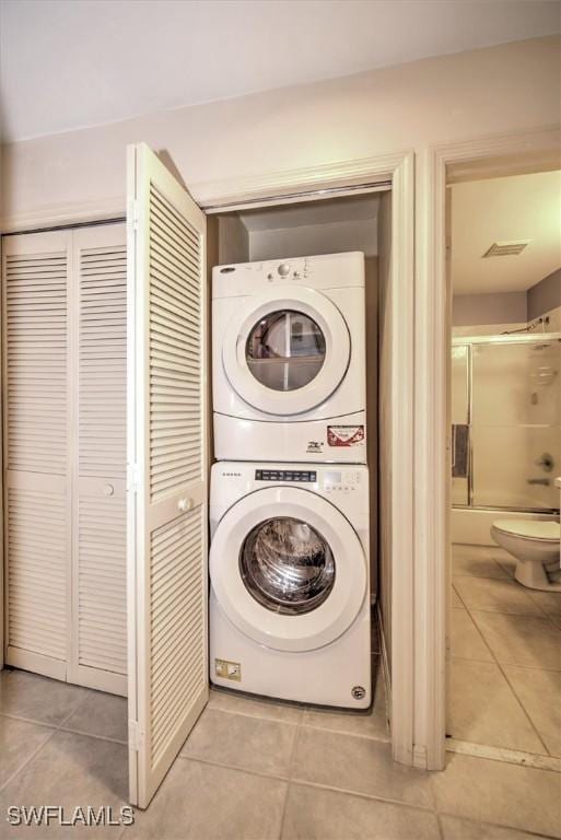 washroom featuring stacked washer / drying machine and light tile patterned floors