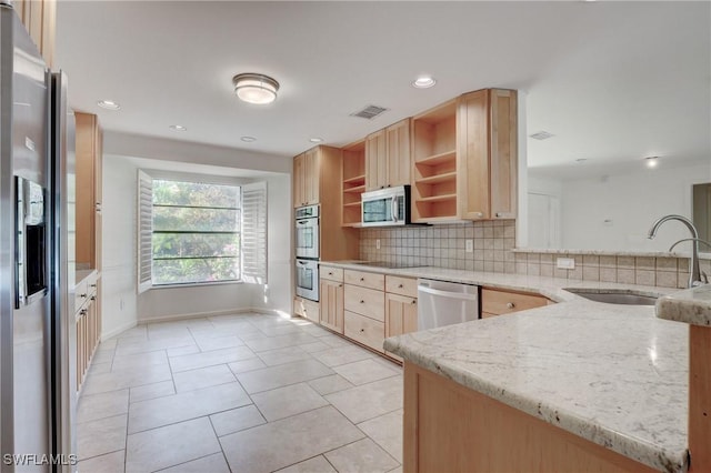 kitchen featuring sink, tasteful backsplash, light brown cabinets, stainless steel appliances, and light stone countertops