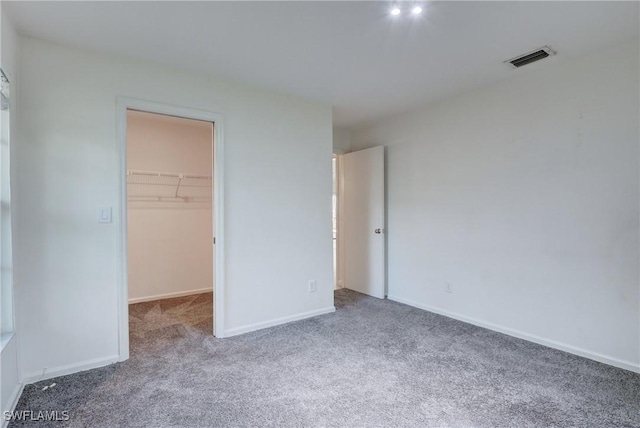 unfurnished bedroom featuring a walk in closet, carpet, and a closet