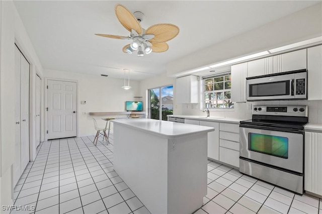 kitchen with a kitchen island, white cabinetry, backsplash, light tile patterned floors, and stainless steel appliances