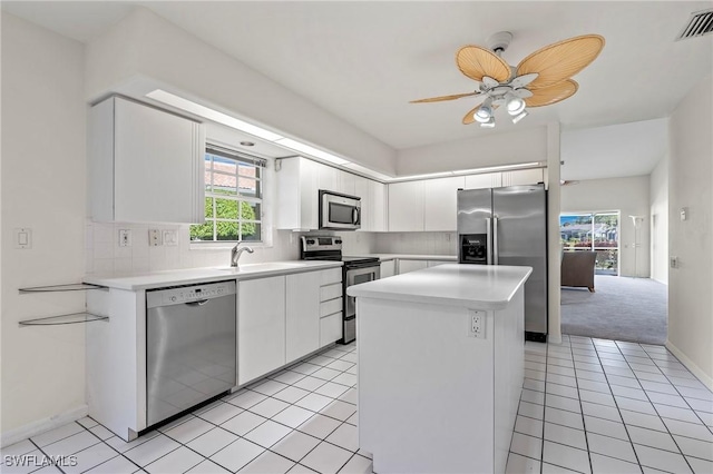 kitchen featuring appliances with stainless steel finishes, white cabinetry, sink, backsplash, and a center island