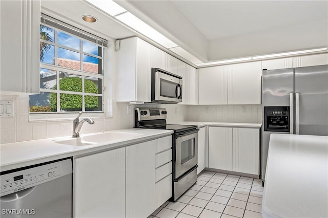 kitchen with tasteful backsplash, appliances with stainless steel finishes, sink, and white cabinets