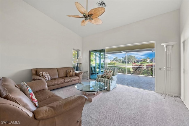 carpeted living room with ceiling fan and high vaulted ceiling