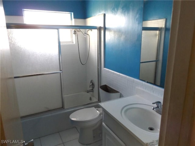 14 Richmond Ave N, Lehigh Acres, FL 33936 - full bathroom featuring toilet, combined bath / shower with glass door, tile walls, vanity, and tile patterned flooring