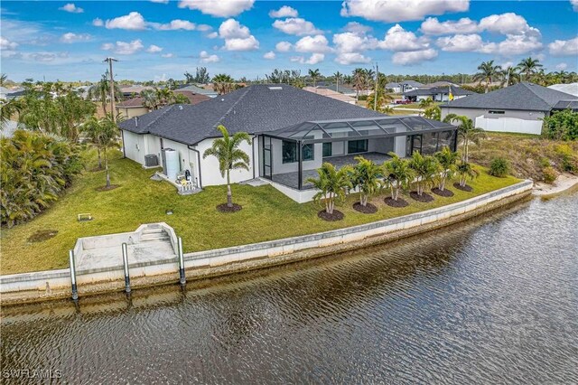 rear view of house featuring a water view, a lanai, and a lawn