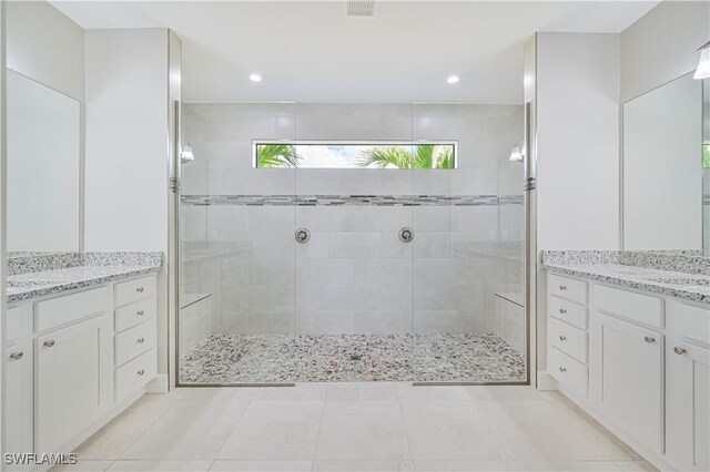 bathroom with tile patterned flooring, vanity, and tiled shower