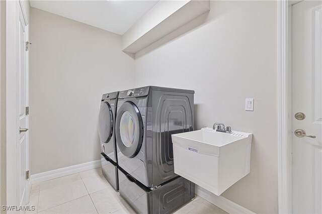 clothes washing area with sink, washing machine and dryer, and light tile patterned floors