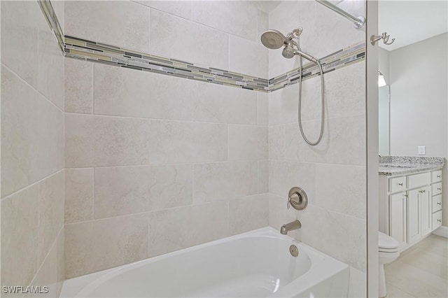 full bathroom featuring tiled shower / bath, vanity, and toilet