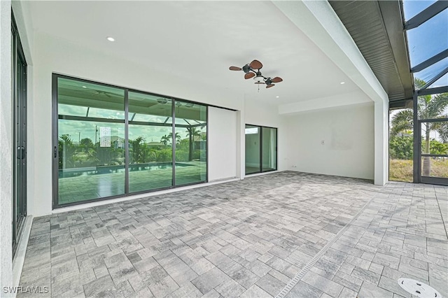 view of patio with ceiling fan and glass enclosure