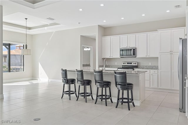 kitchen featuring a kitchen island with sink, a breakfast bar area, light stone countertops, and appliances with stainless steel finishes