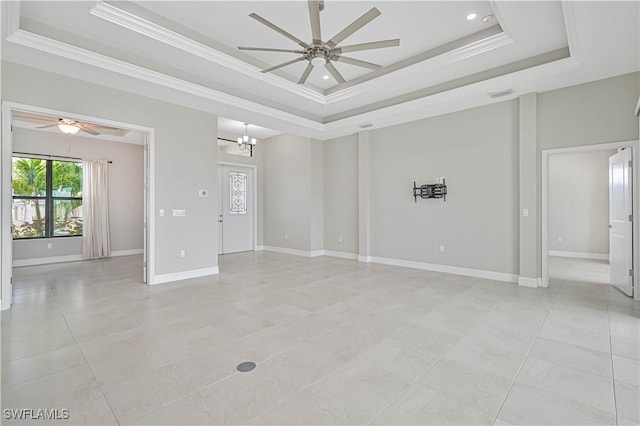 empty room featuring ceiling fan with notable chandelier, ornamental molding, a raised ceiling, and a high ceiling