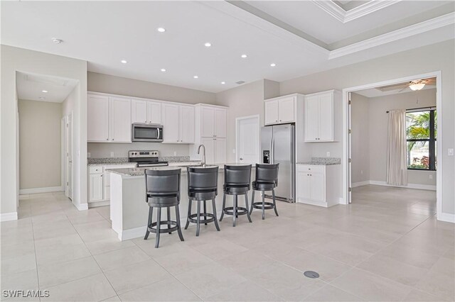 kitchen featuring white cabinetry, a breakfast bar, an island with sink, and appliances with stainless steel finishes