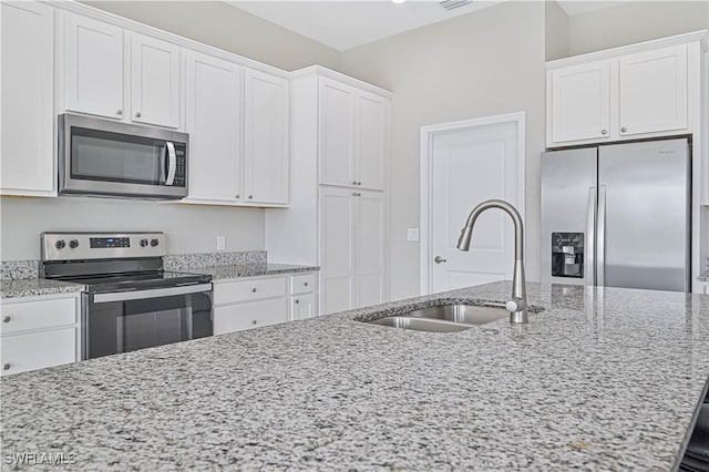 kitchen with white cabinetry, appliances with stainless steel finishes, light stone countertops, and sink