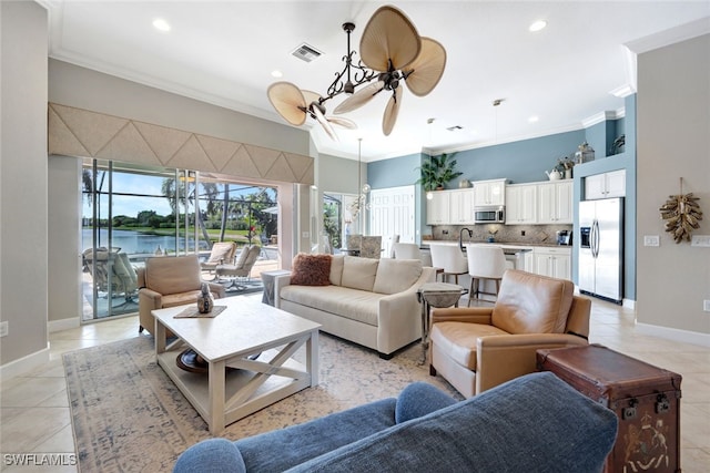 tiled living room featuring ornamental molding, ceiling fan, and a water view