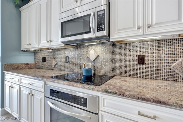 kitchen with light stone countertops, appliances with stainless steel finishes, white cabinets, and backsplash