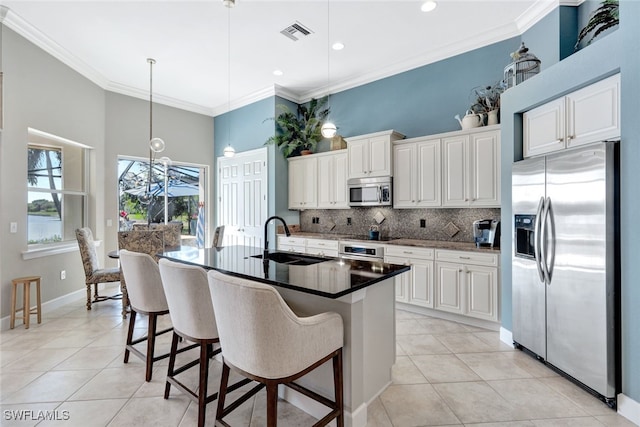 kitchen with sink, appliances with stainless steel finishes, hanging light fixtures, white cabinets, and a center island with sink