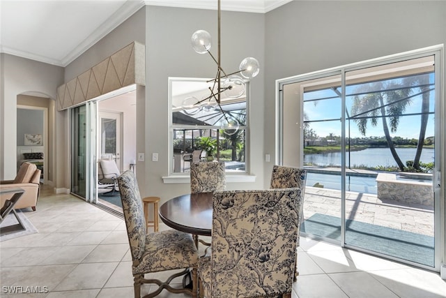 dining area featuring an inviting chandelier, light tile patterned flooring, ornamental molding, and a water view