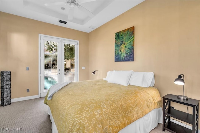 carpeted bedroom featuring access to exterior, ceiling fan, and a tray ceiling