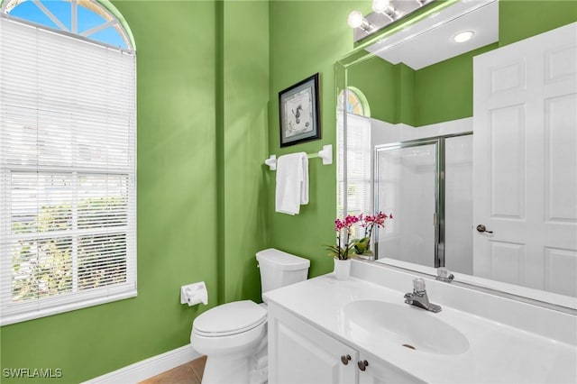 bathroom with tile patterned flooring, vanity, a wealth of natural light, and a shower with shower door