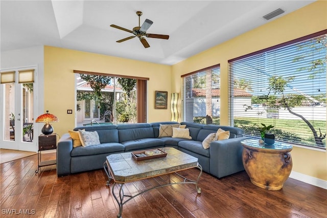 living room with a raised ceiling, dark hardwood / wood-style floors, and ceiling fan