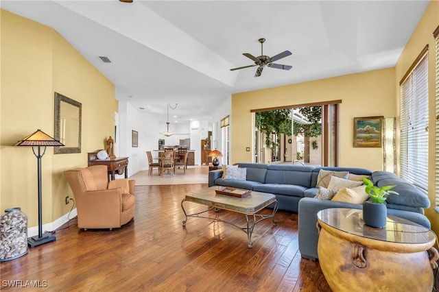 living room featuring wood-type flooring, a raised ceiling, and ceiling fan