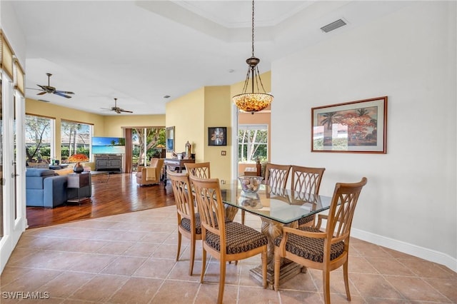 dining area with light tile patterned floors, plenty of natural light, and a raised ceiling