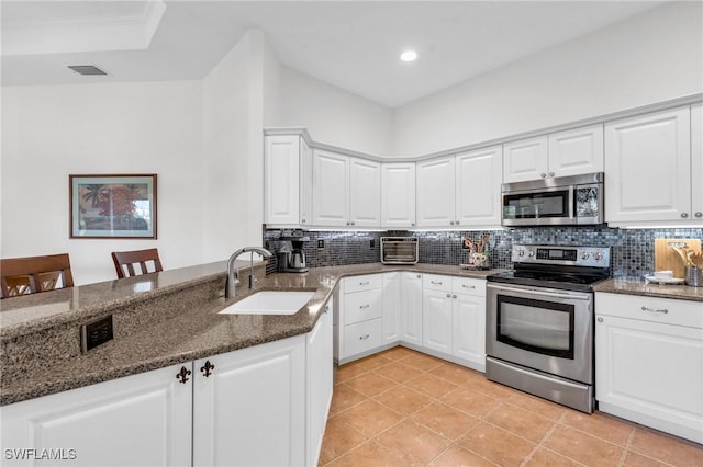 kitchen featuring dark stone countertops, appliances with stainless steel finishes, sink, and white cabinets