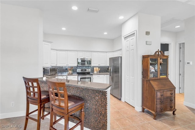 kitchen featuring stainless steel appliances, tasteful backsplash, white cabinets, and kitchen peninsula