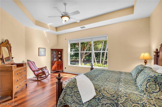 bedroom featuring ceiling fan, a raised ceiling, and hardwood / wood-style floors