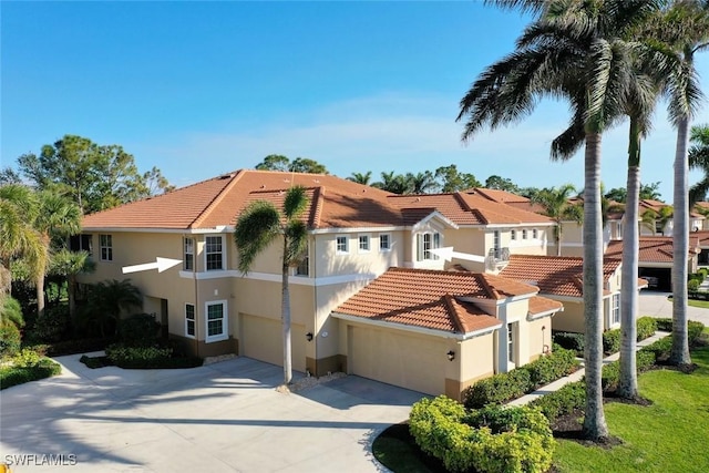 mediterranean / spanish house featuring stucco siding, concrete driveway, and a tiled roof